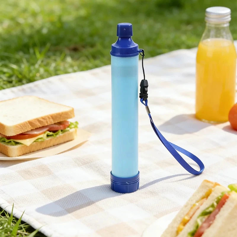 Blue Portable Water Filter Straw on a picnic blanket with sandwiches and juice.
